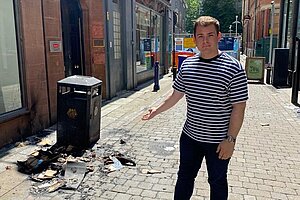 Luke_Allan_DG_Burned_Litter_Ridgefield_Street Luke stood next to a litter bin on Ridgefield Street surrounded by burnt cardboard.