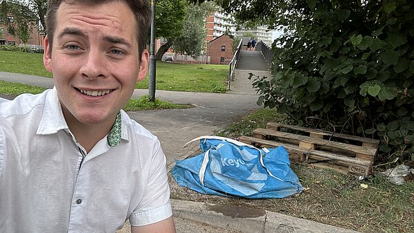 Luke crouching beside fly-tipping