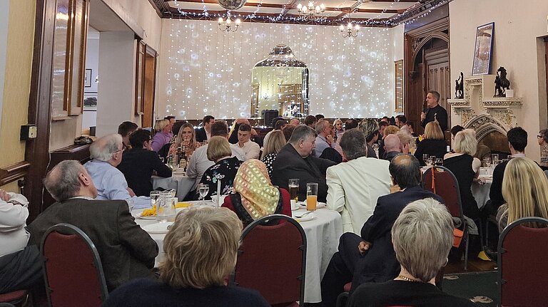 A group of people watch a speaker