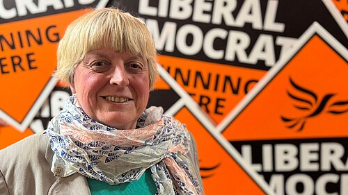 Liberal Democrat Candidate Jackie Pearcey in front of a sea of Lib Dem diamonds